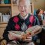 Grandfather looking at old albums with family photos. Retirement and passage of time, memories of youth, family mementos, memory loss.